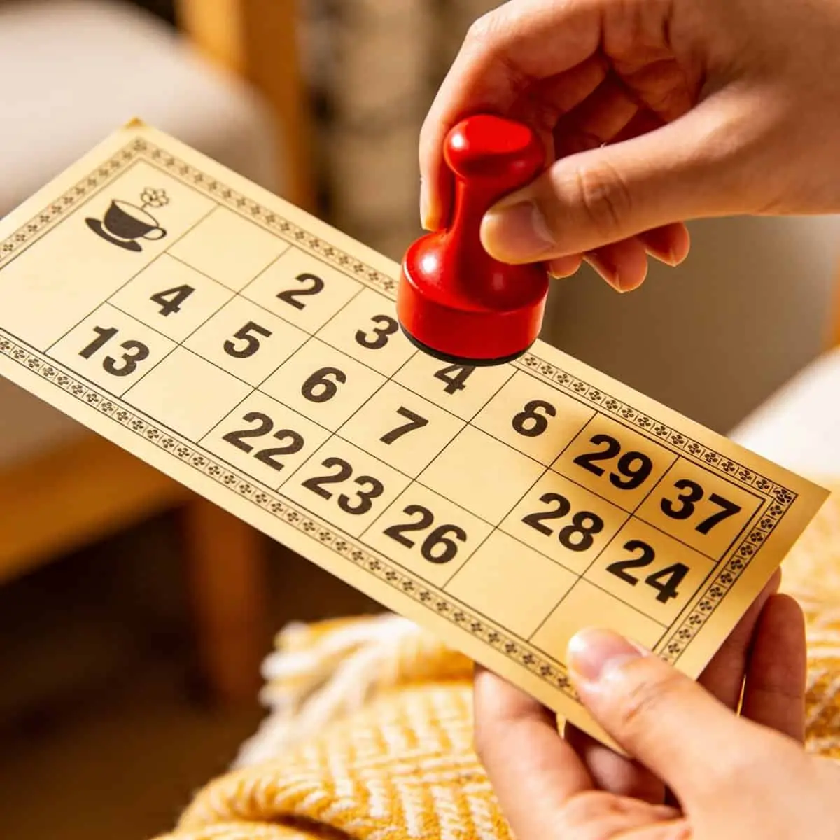Hand holding a clear, custom-designed bingo card with a dabber ready.